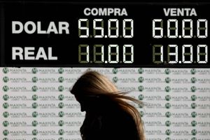 A woman walks past a currency exchange board in Buenos Aires, Argentina, Monday, Aug. 12, 2019. The peso devalued sharply on Monday in Argentina after a striking victory by the opposition in Sunday's presidential primaries ahead of October's presidential elections. (AP Photo/Natacha Pisarenko)