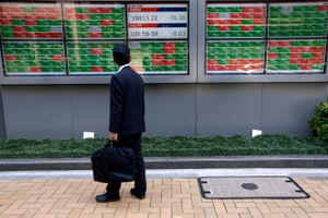 På vej til arbejde studerer en japansk forretningsmand udviklingen i Nikkei-aktieindekset. Japan har den største offentlige gæld i verden på 228 pct. af bruttonationalproduktet. Foto: AP/Eugene Hoshiko