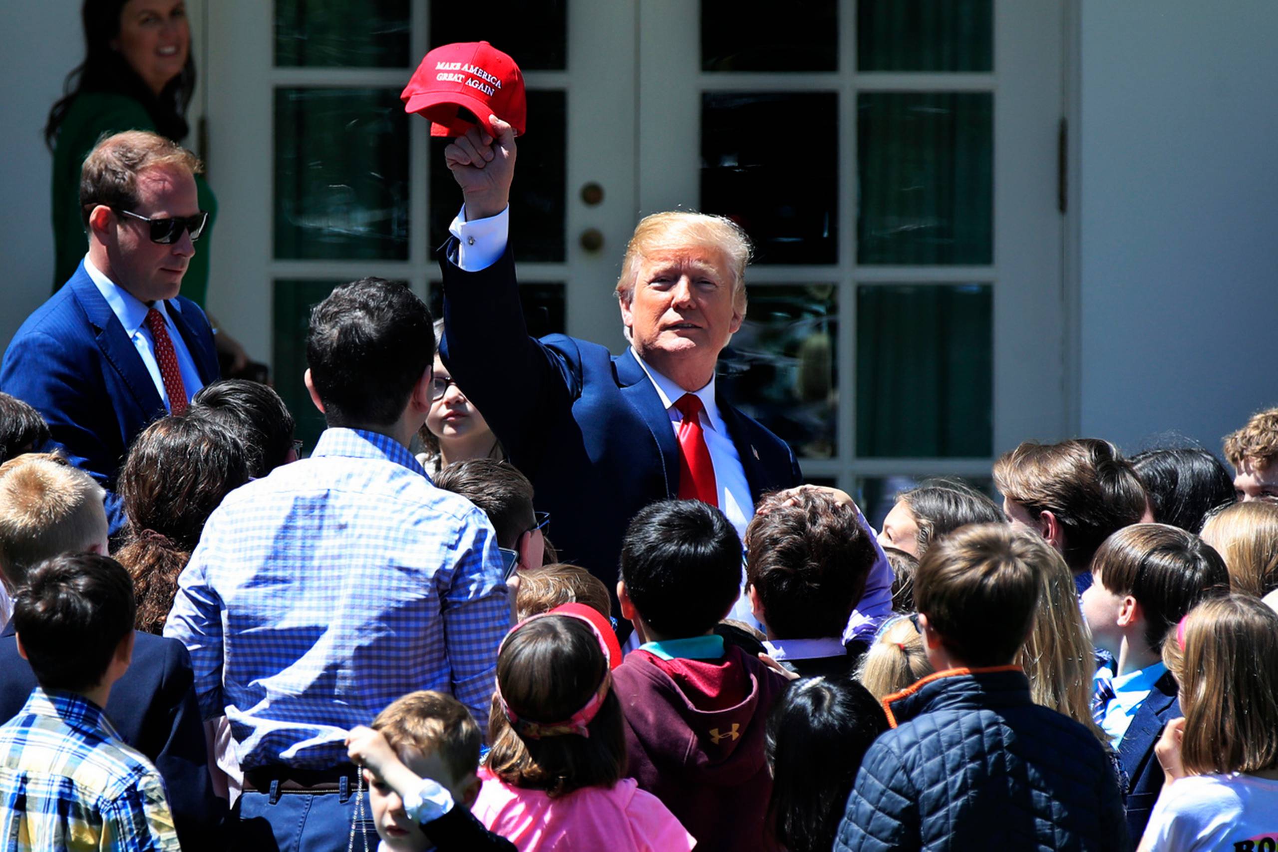 Trump holder en "Make America Great Again-kastet" op foran børn i Det Hvide Hus rosenhave, som er på besøg i forbindelse med "tag dine børn med på arbejde-dag." Tidligere på morgenen gav han et kaotisk telefoninterview til hans yndlings tv-program Fox & Friends. Foto: AP/Manuel Balce Ceneta