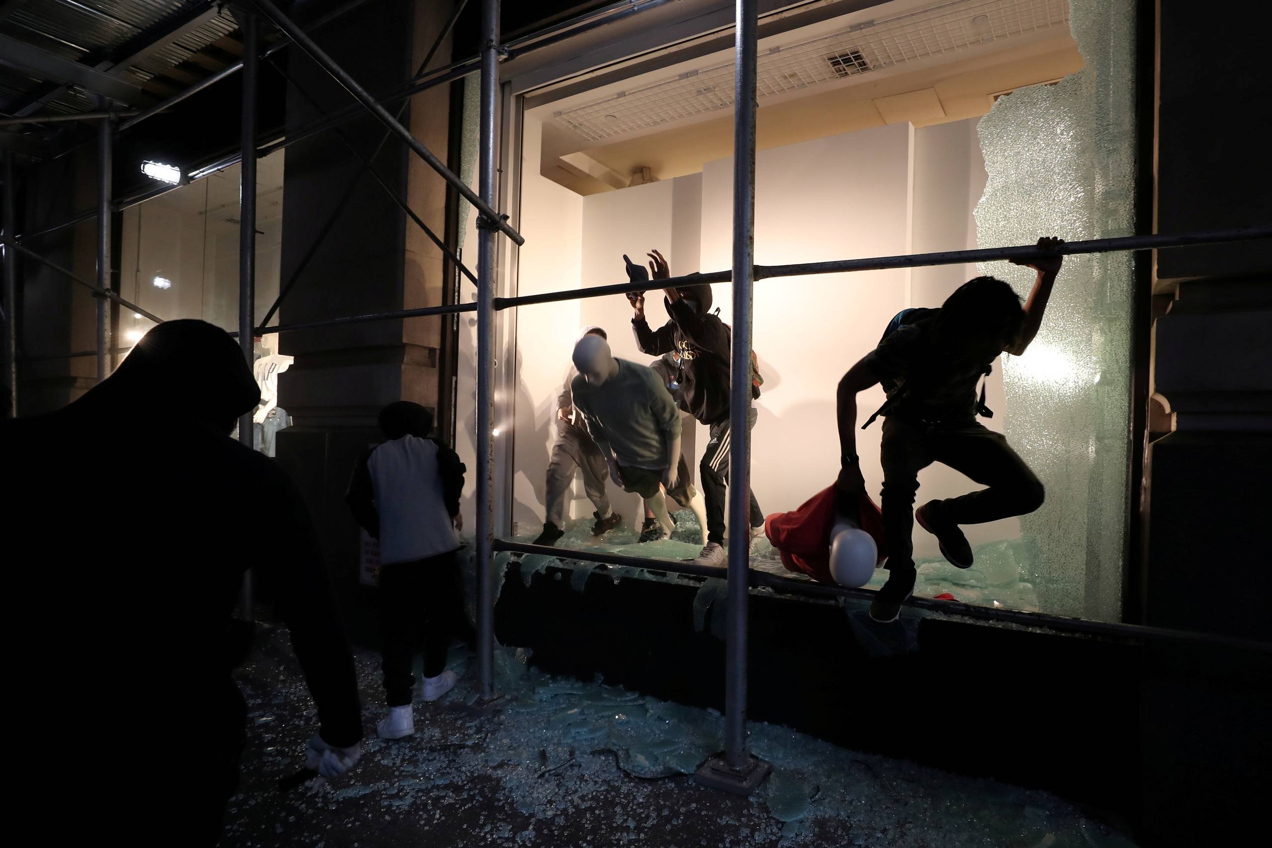En mand springer ud af et smadret butiksvindue i New York. Foto: Jeenah Moon
