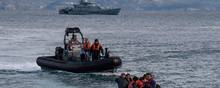 A dinghy with 15 Afghan refugees, 5 children, 3 women and 7 men, approaches the Greek island of Lesbos on February 28, 2020 next to UK Border Force patrol boat HMC Valiant (background), a cutter patroling in Agean sea under European Union border force Frontex. - Turkey will no longer close its border gates to refugees who want to go to Europe, a senior official told AFP on February 28, shortly after the killing of 33 Turkish soldiers in an airstrike in northern Syria. (Photo by ARIS MESSINIS / AFP)