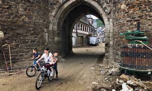 Tre børn kører igennem porten i den gamle bymur fra 1200-tallet i Ahrweiler. Byen er totalt ødelagt og står uden strøm og vand, og samtlige butikker i den gamle bymidte er lukket. Foto: Heidi Plougsgaard