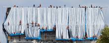Det krævede kraner og flere hundrede arbejdere at rulle stoffet ned over Triumfbuen. Foto: Thomas Samson / AFP