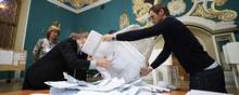 Valgtilforordnede tømmer en kasse med stemmesedler inden optællingen af stemmer ved det russiske parlamentsvalg. Foto: Evgenia Novozhenina/Reuters