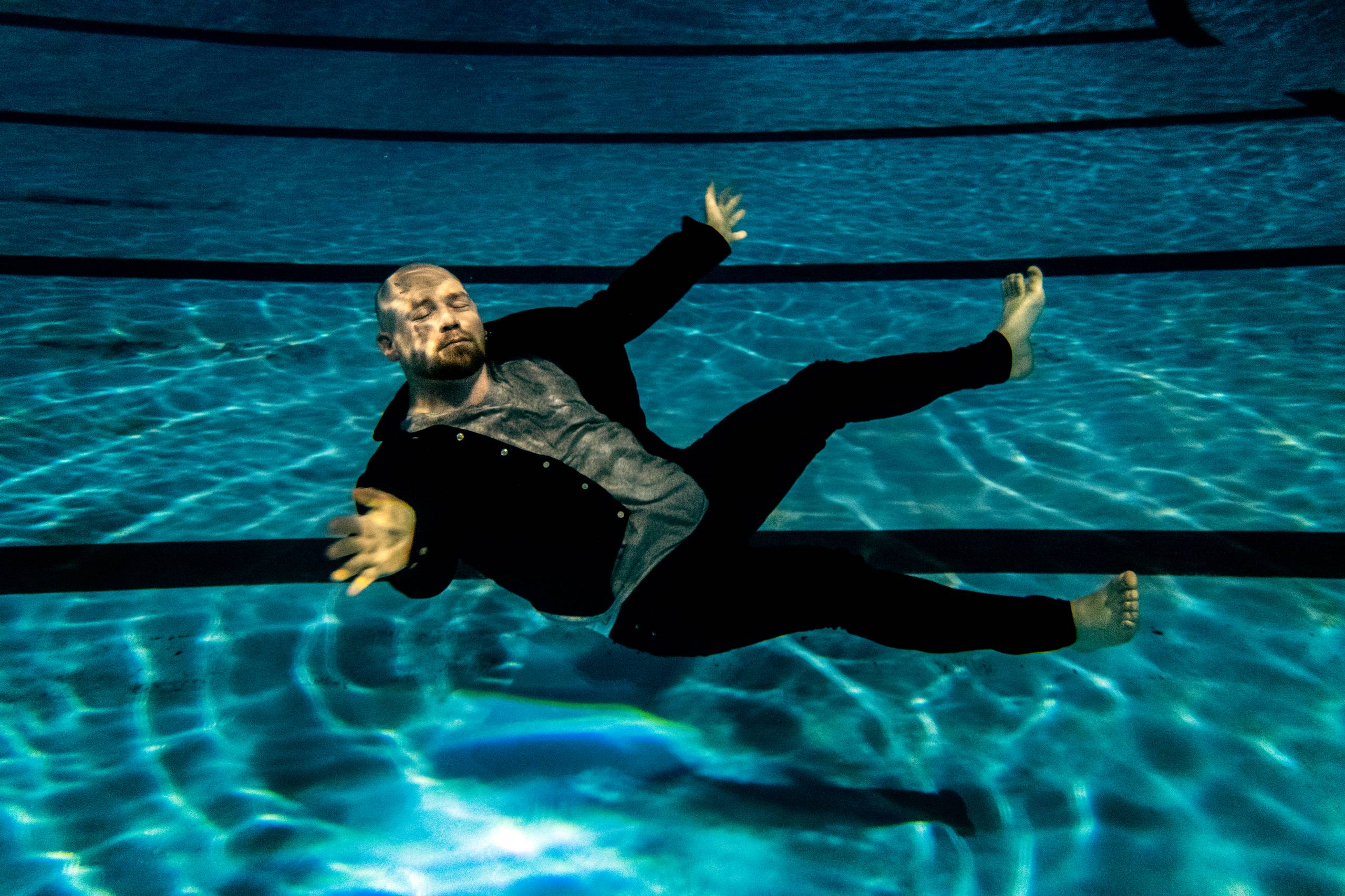 Egentlig var fotograferingen af Morten Pape  til coverhistorien på JP Bøger slut den torsdag eftermiddag, da han siger, at han har set, at jeg flere gange har fotograferet personer under vand. »Klor er jo lugten af min barndom, for min mor er jo bademester,« siger han, og så er der jo ingen vej tilbage. 6.45 næste morgen står vi ved den lille, slidte svømmehal på Amager, hvor vi får 30 minutter, inden skolebørn vælter ind. Morten er overrasket over, hvor tungt hans tøj bliver under vand, og hvor svært det er at holde øjnene åbne, og jeg kæmper med lyset, eller manglen på samme, og er glad for den lygte, jeg har snuppet med fra min mands værktøjskasse. Efter 16 minutter og knap 200 skud er der pludselig sort skærm på kameraet, og jeg opdager at der står 3 cm vand inden i plastickassen, der skulle beskytte kameraet. Alt er vådt, og kameraet helt dødt, så det er bare ud med  memorykortet og håbe på, at det ikke har taget skade. Heldigvis findes billederne, og jeg kan godt lide den ro og det barnlige smil, der er hos Amagerdrengen under vandet.  Foto: Stine Bidstrup