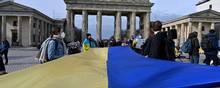 Overalt i Vesten er fordømmelsen mod Putins angreb på Ukraine entydig, som her foran Brandenburger Tor i Berlin, hvor demonstranter foldede det ukrainske flag ud i protest. Foto: John Macdougall/AFP