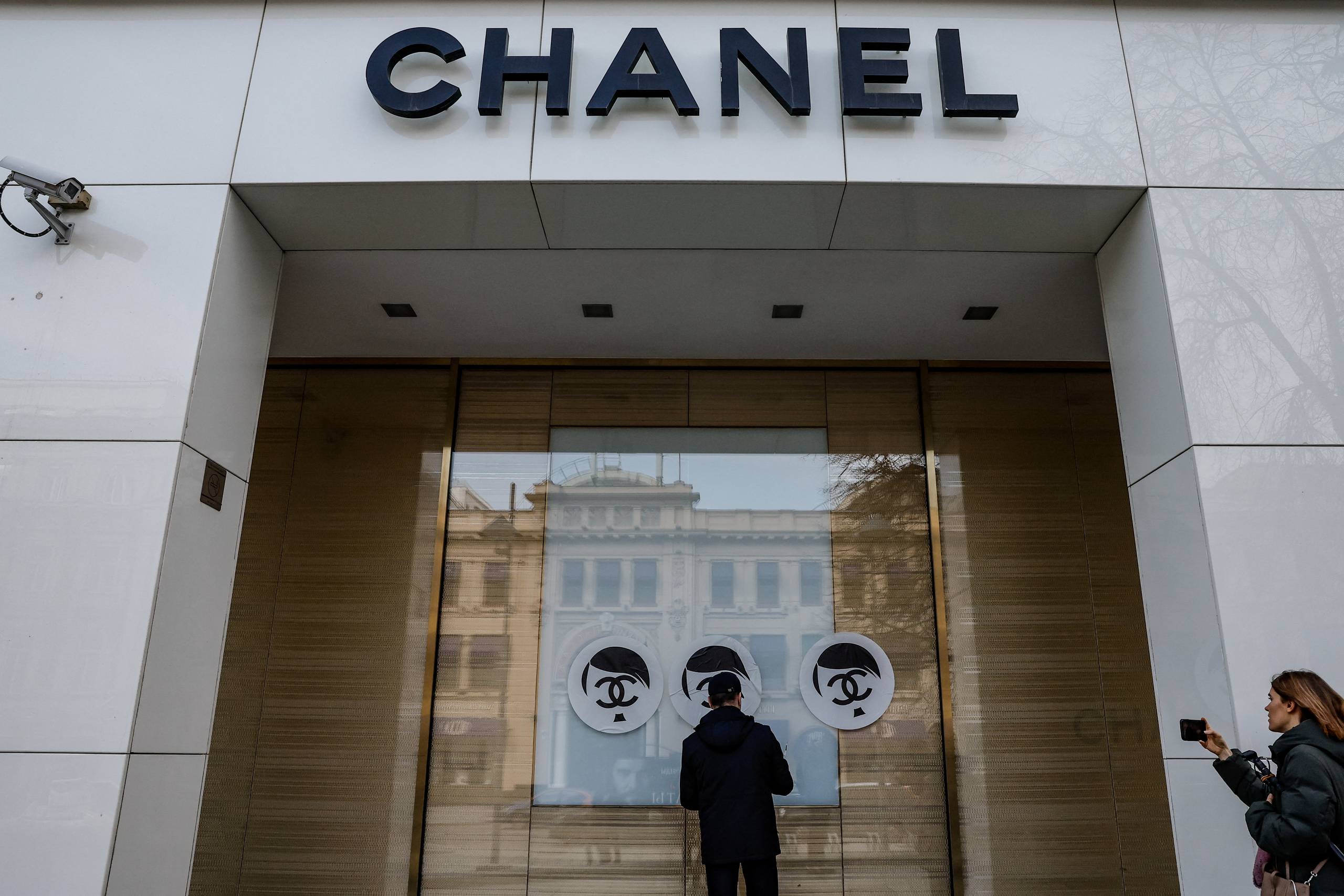 En sikkerhedsvagt forsøger at fjerne de stickers, som var blevet klæbet på Chanels butiksfacade i Moskva. Foto: Maxim Shemetov/Reuters