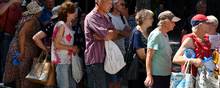 People wait in a line to receive food at a humanitarian aid distribution point in Zaporizhzhia, Ukraine, Tuesday, Aug. 9, 2022. (AP Photo/Andriy Andriyenko)