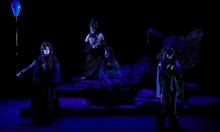 Ditte Marie Tygesens mørke, røgfyldte scenografi og skæve kostumedesign giver ”Antigone” et tegnefilmslignende skær. Foto: Allan Toft
