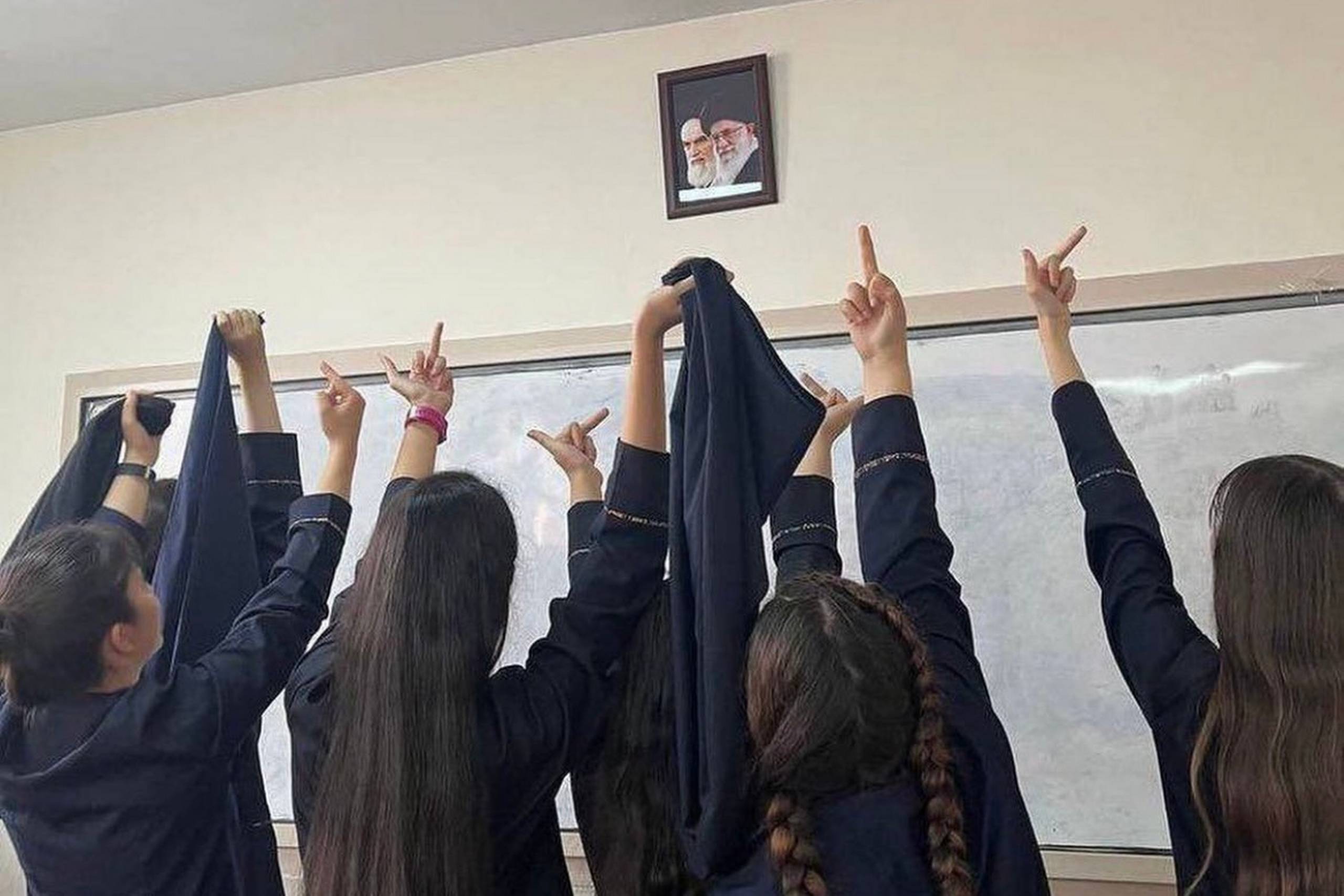 Et billede fra de sociale medier, viser skolerpiger i Iran give fingeren til et billede af landets øverste leder og hans forgænger. Foto: X