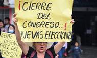 En tilhænger af Perus afsatte præsident Pedro Castillo holder et banner med teksten "Luk Kongressen, nyvalg" under en demonstration torsdag udenfor det arresthus, hvor Castillo har været indsat siden onsdag. Foto: Ernesto Benavides/Ritzau Scanpix