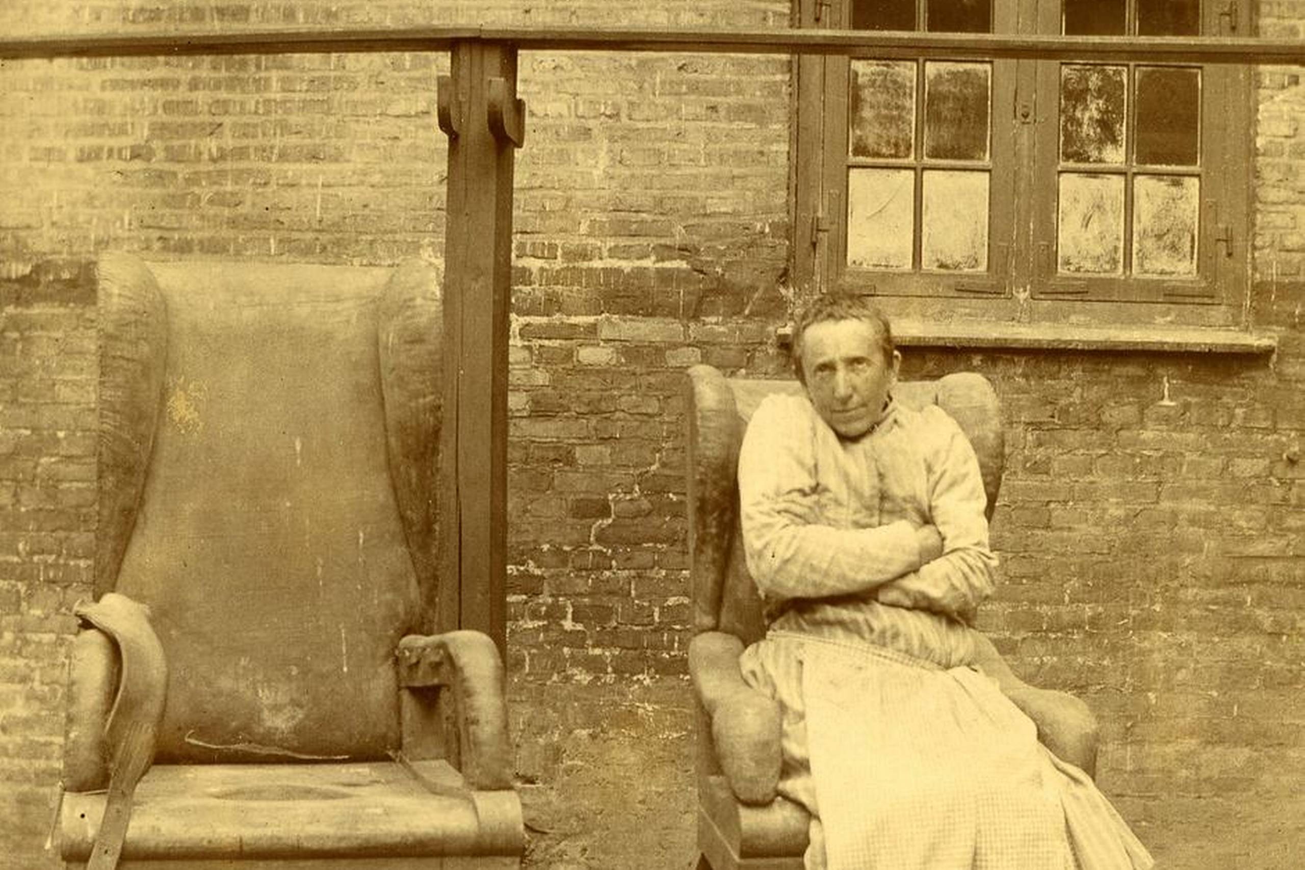 Slutningen af 1800- tallet. En kvindelig patient sidder i tvangsstol, dog uden at være fikseret. Til venstre er en større stol med åbning i sædet og en potte nedenunder, så hun kunne forrette sin nødtørft. Aarhus Universitetshospital, Risskov