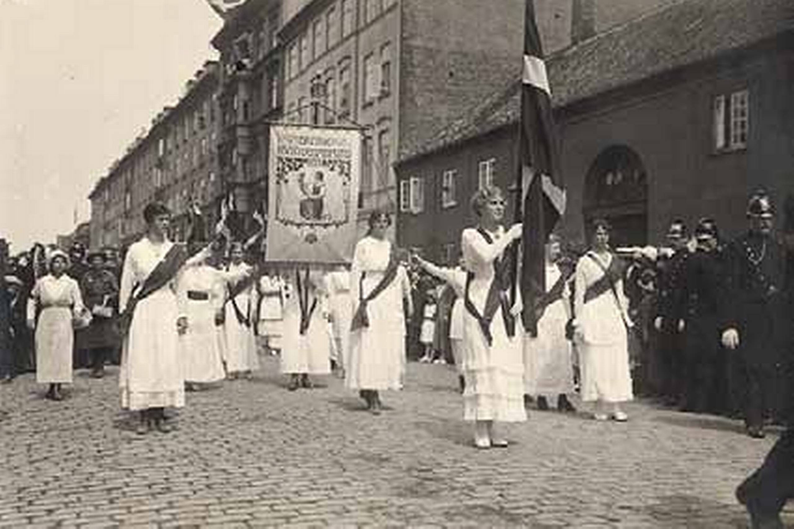 Dansk Kvindesamfund fra 1871 var den første og største forening, der kæmpede for kvindernes ligestilling. På billedet frembæres dets fane i triumf på toget til Amalienborg efter opnåelsen af kvindelig valgret i 1915. Foto: Københavns Museum