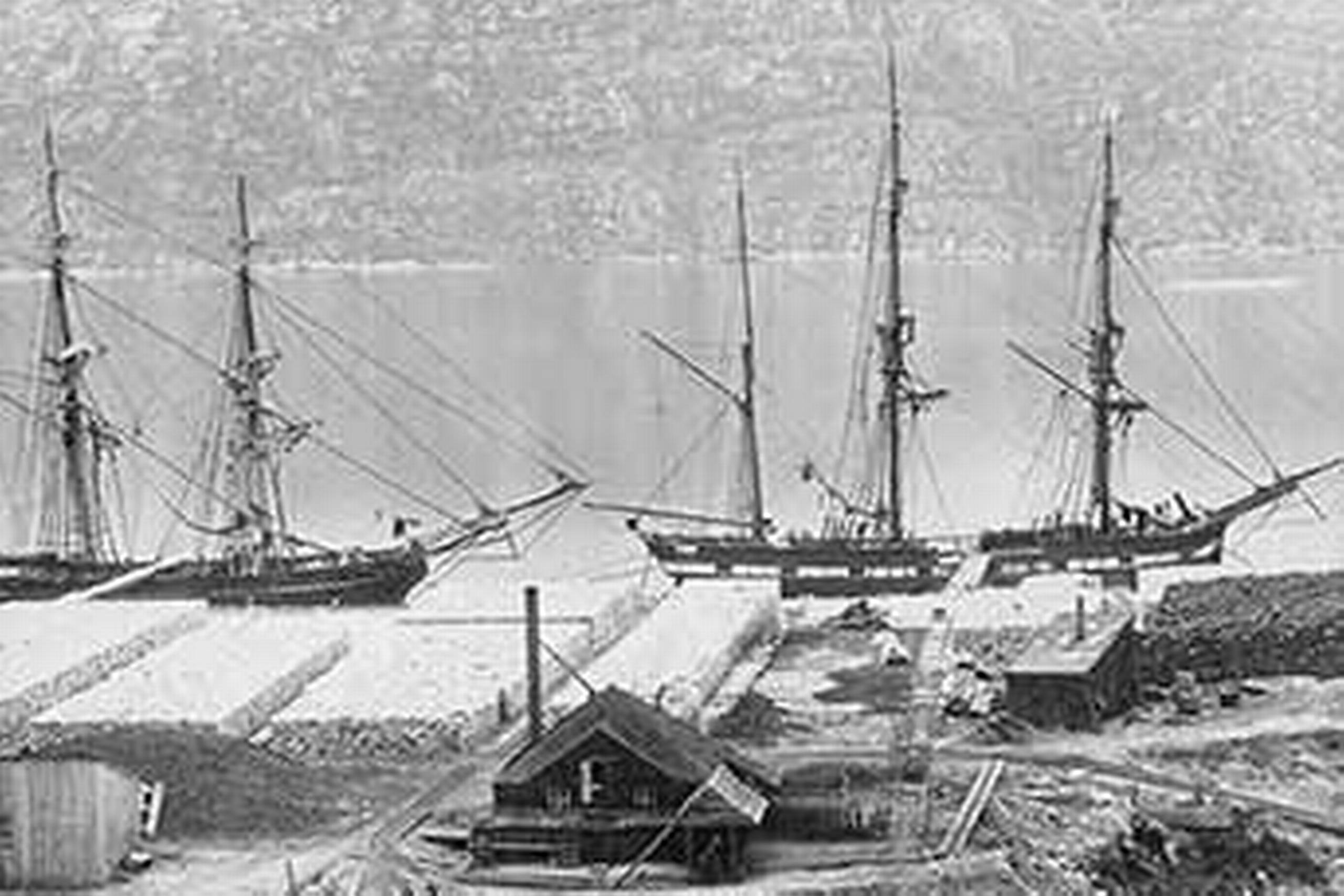 Udskibning af kryolit fra Ivittuut, 1870. Sejlskibene er klar til at blive losset med kryolitsække og tage til København.