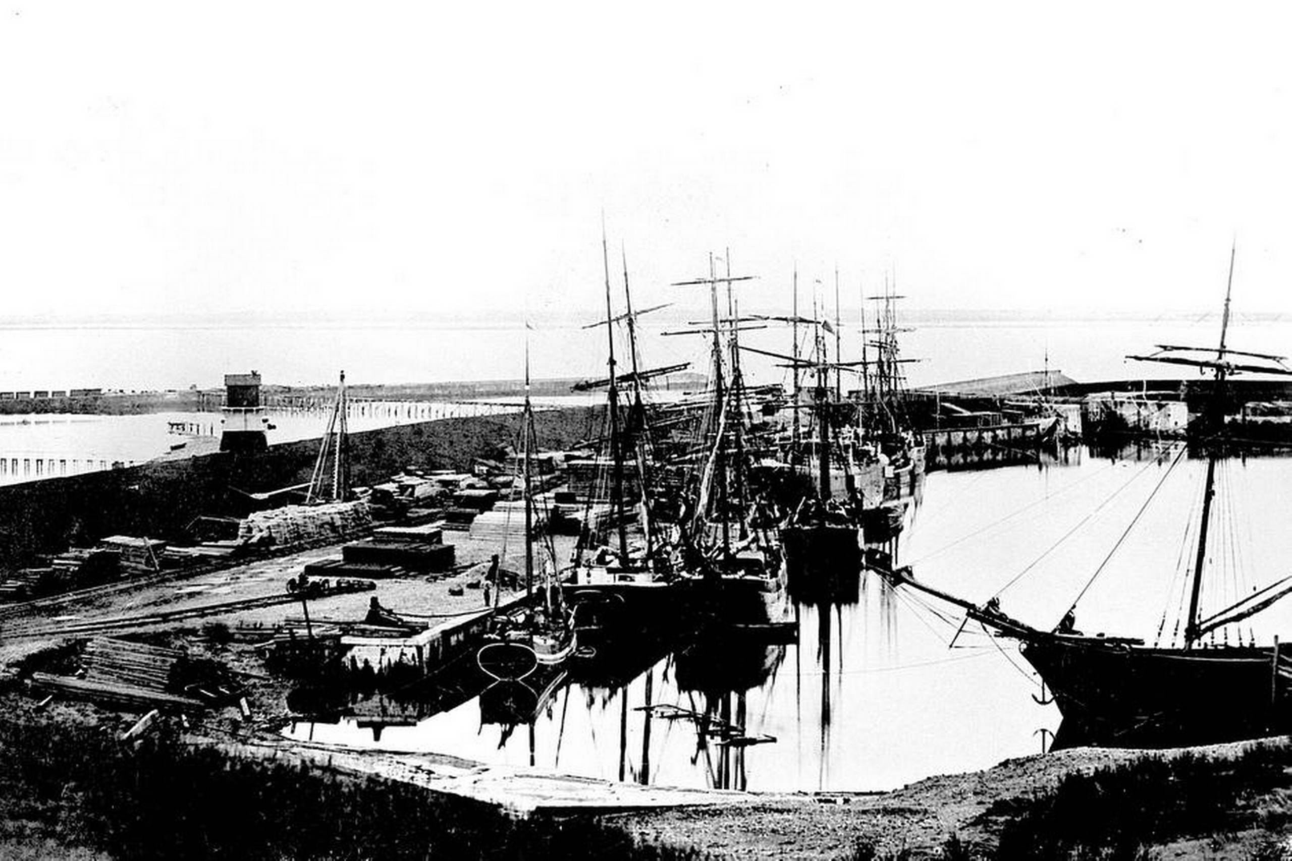 Esbjerg Havn åbnede officielt for besejling i august 1874. Havnen var på det tidspunkt langt fra færdigbygget, hvilket anes på dette foto. I billedets venstre side ses på dokdiget det ene af havnens ledefyr. Foto: Fiskeri- og Søfartsmuseet i Esbjerg
