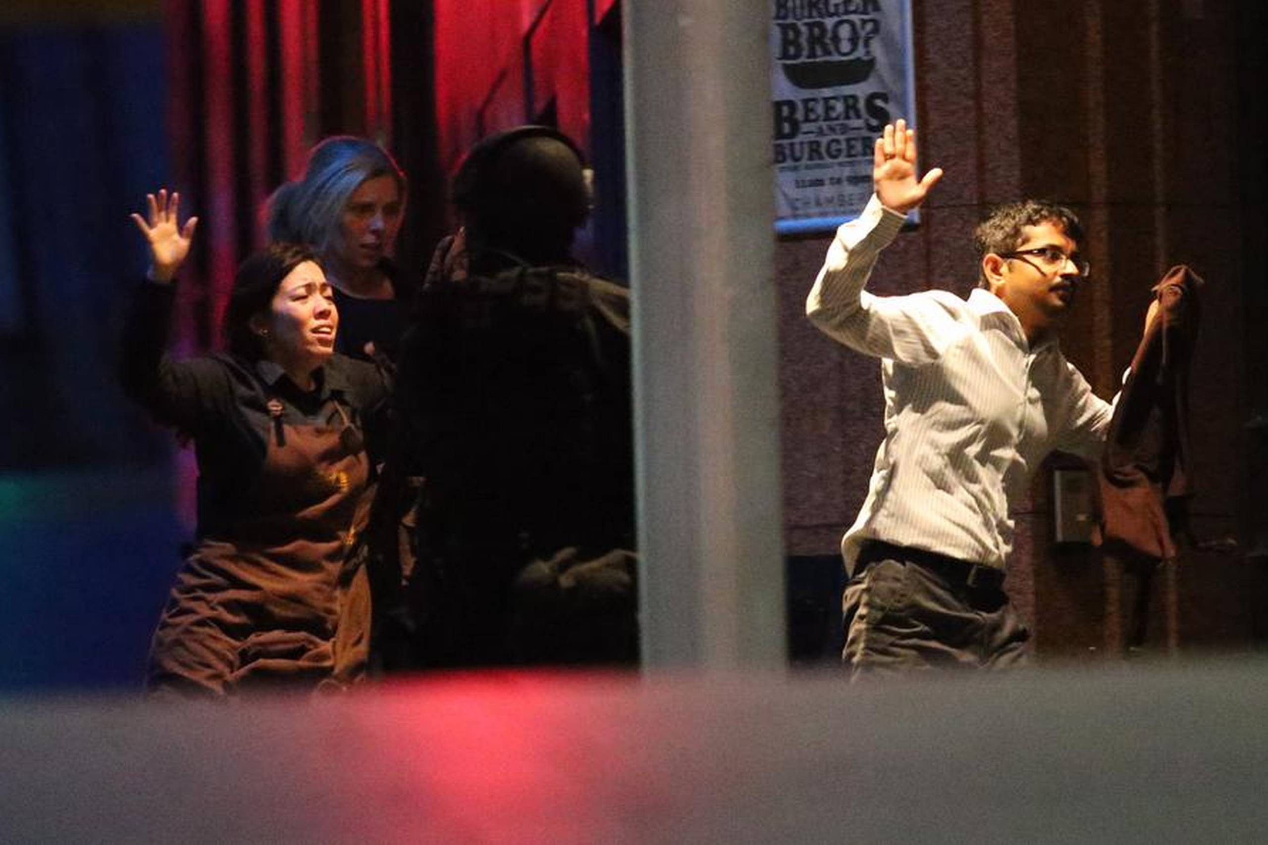 Rædselsslagne gidsler flygtede med hænderne i vejret, da antiterrorkorpset natten til tirsdag (lokal tid) stormede caféen i Sydney og dræbte gidseltageren. Foto: Rob Griffith/AP