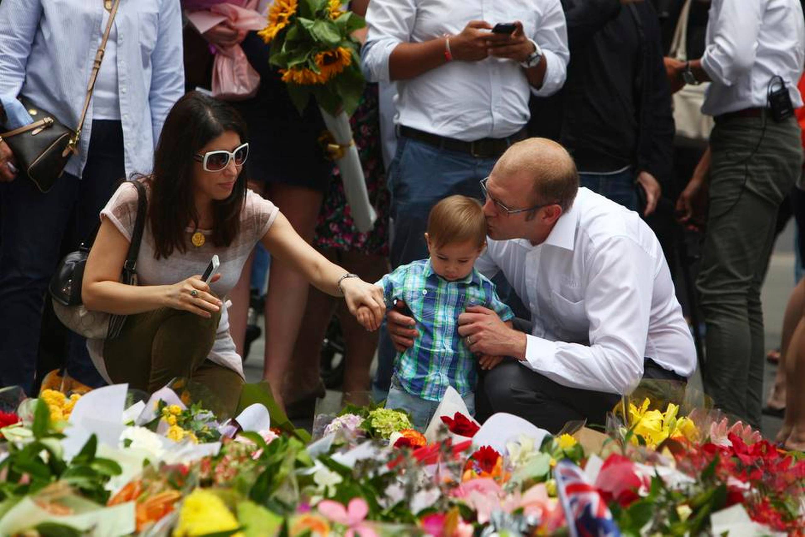 Tusinder af australiere var i løbet af tirsdagen forbi den sønderskudte og afspærrede café. Politiet har sat hegn op foran facaden, men asfalten var helt dækket af blomsterbuketter. Foto: Steve Christo/AP