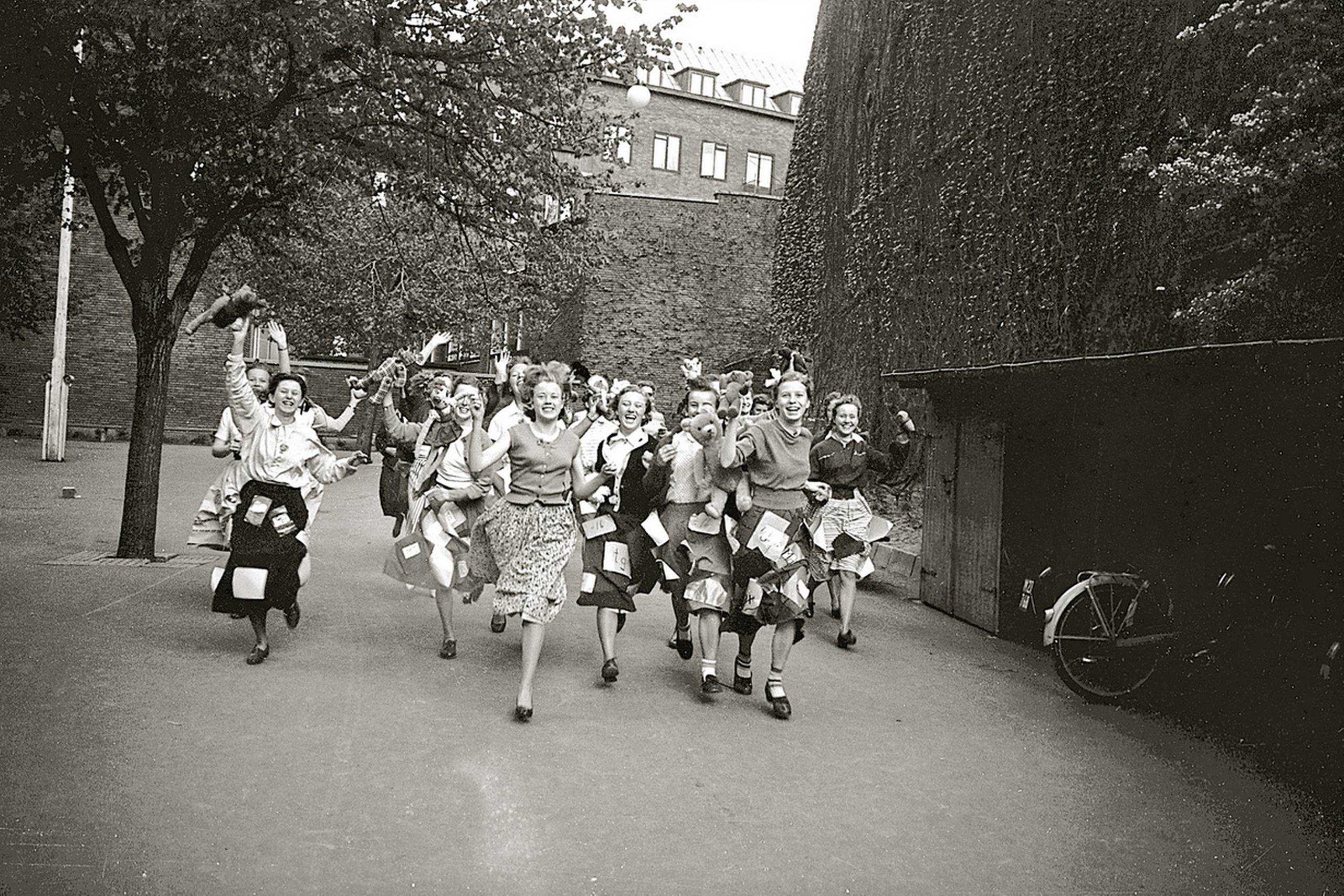 Efter Anden Verdenskrig overhalede pigerne i procent drengene i både mellemskolen og i realskolen. Her fejres sidste skoledag for afgangseleverne i Odense Kommunale Pigerealskole i maj 1956. Dukkernes og bamsernes tid var endegyldigt forbi, selvom de havde fået lov til at komme med på billedet. Forude ventede eksamenslæsning, en kontorplads eller – for ganske få – gymnasiet. 