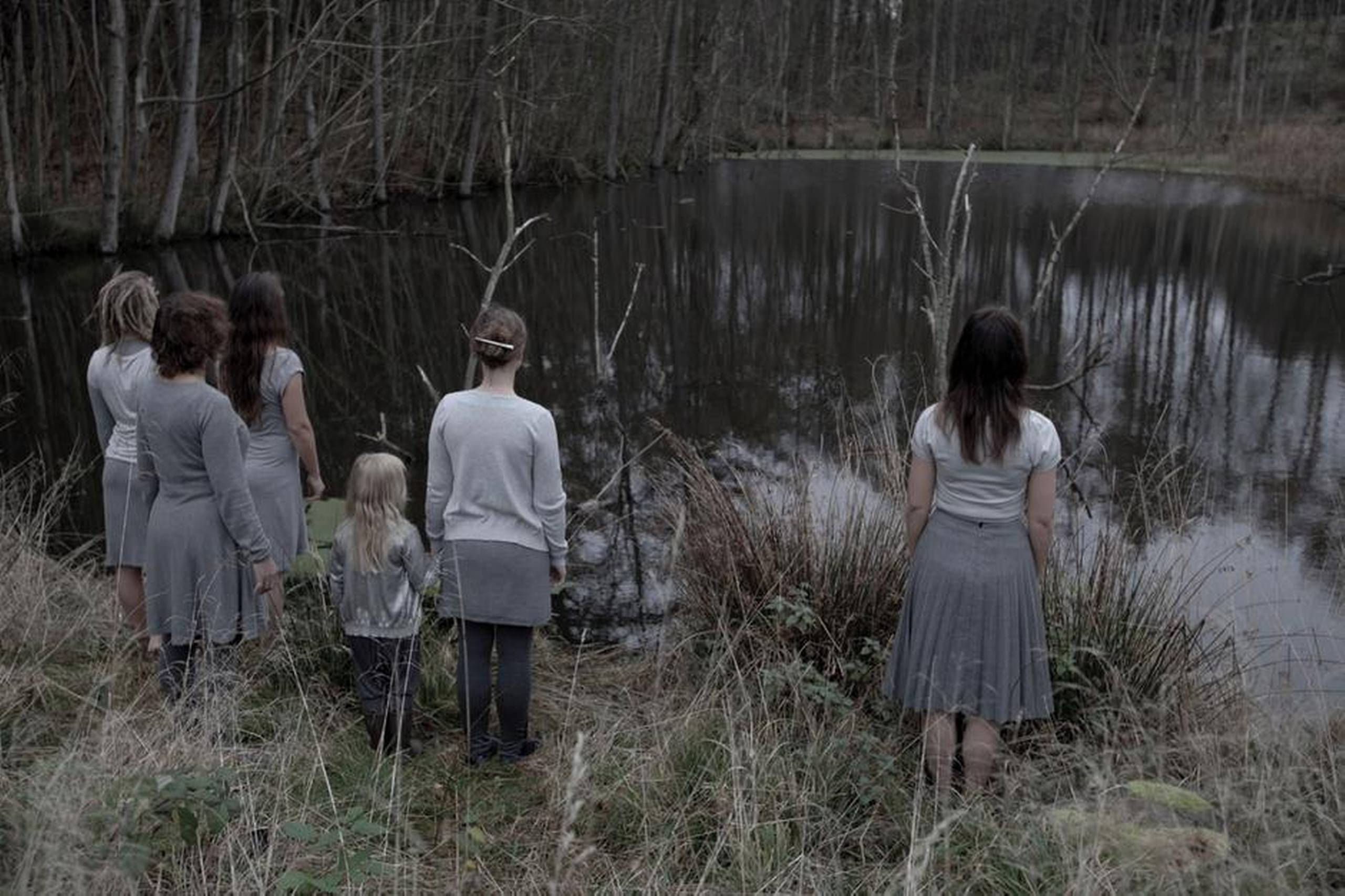 Fem voksne kvinder og en pige udlever hverdagens grå og regnvåde tristesse i Katja Bjørns videokunst ”Grå” på Randers Kunstmuseum. Pressefoto: Randers Kunstmuseum