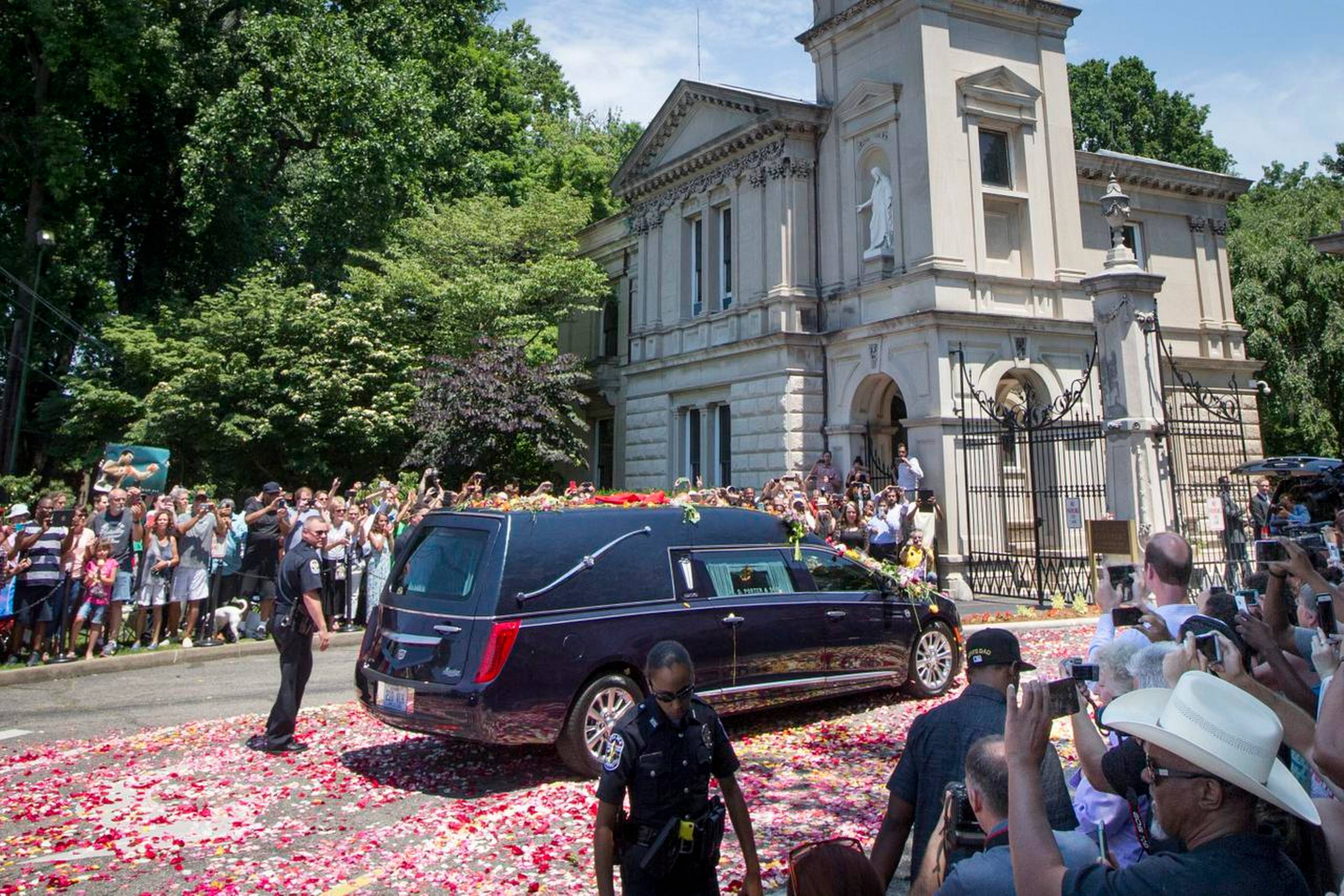 The hearse carrying Muhammad Ali arrives as spectators watch his funeral procession enter Cave Hill Cemetery, Friday, June 10, 2016, in Louisville, Ky. (AP Photo/John Minchillo)