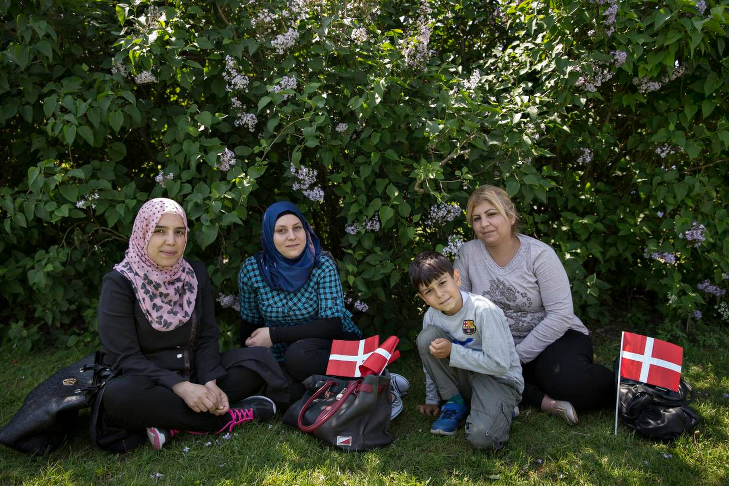 Khawla Al Kathawi (t.v.), Yasmin Sahyouni, Mawlod Mohamad har sat sig i skyggen uden for Integrationsteamet i Favrskov Kommune i Hadsten sammen med Mohammed, der er søn af Yasmin Sahyouni. Kvinderne deltog i en demonstration i protest over, at de ikke får sommerferie. Foto: Christian Klindt Sølbeck
