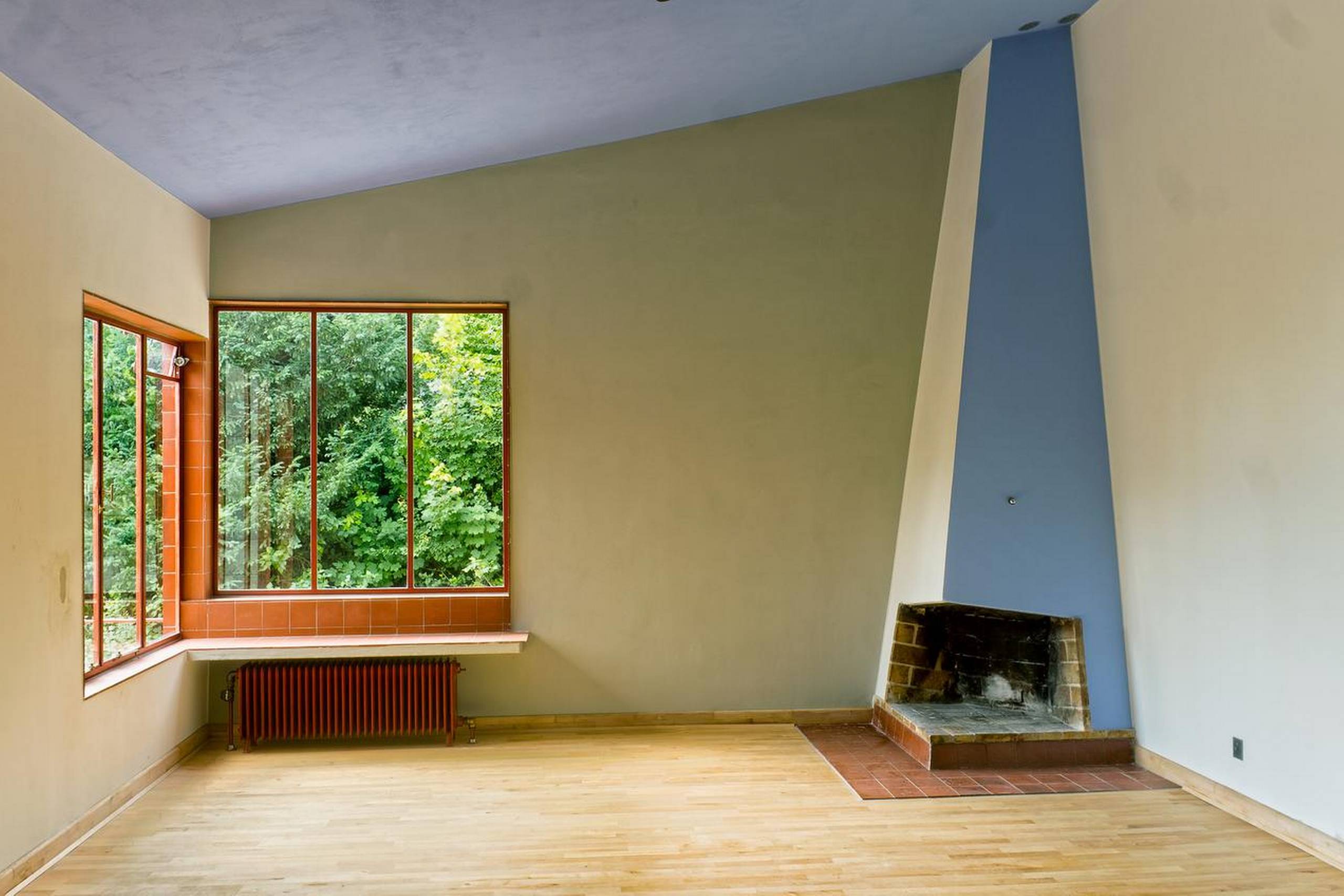 Den røde farve i stuens vinduer og radiator er en gennemgående farve i huset. Det samme er den blå farve loftet og ned langs pejsens ene side.