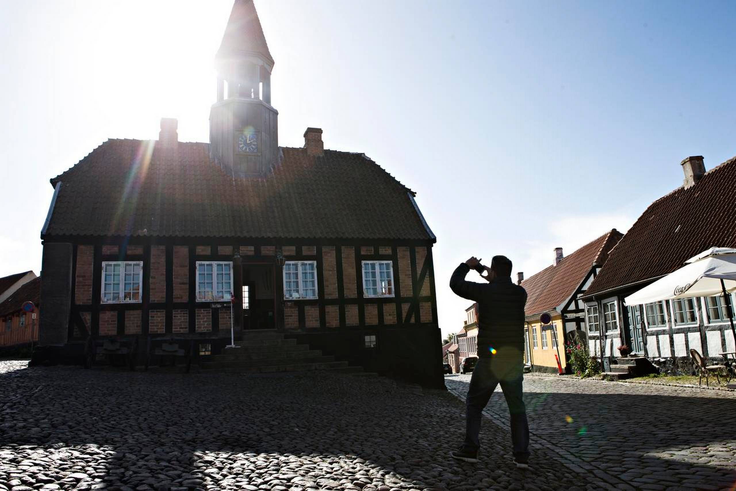 I Ebeltoft står bindingsværkshuse på række langs brostensgader, og man kan bl.a. møde vinhandleren, der taler om at leve i et land, hvor der er både demokrati og tillid nok mellem mennesker, til at han kan lade en palle vin stå ude på gaden. Foto: Tobias Nicolai