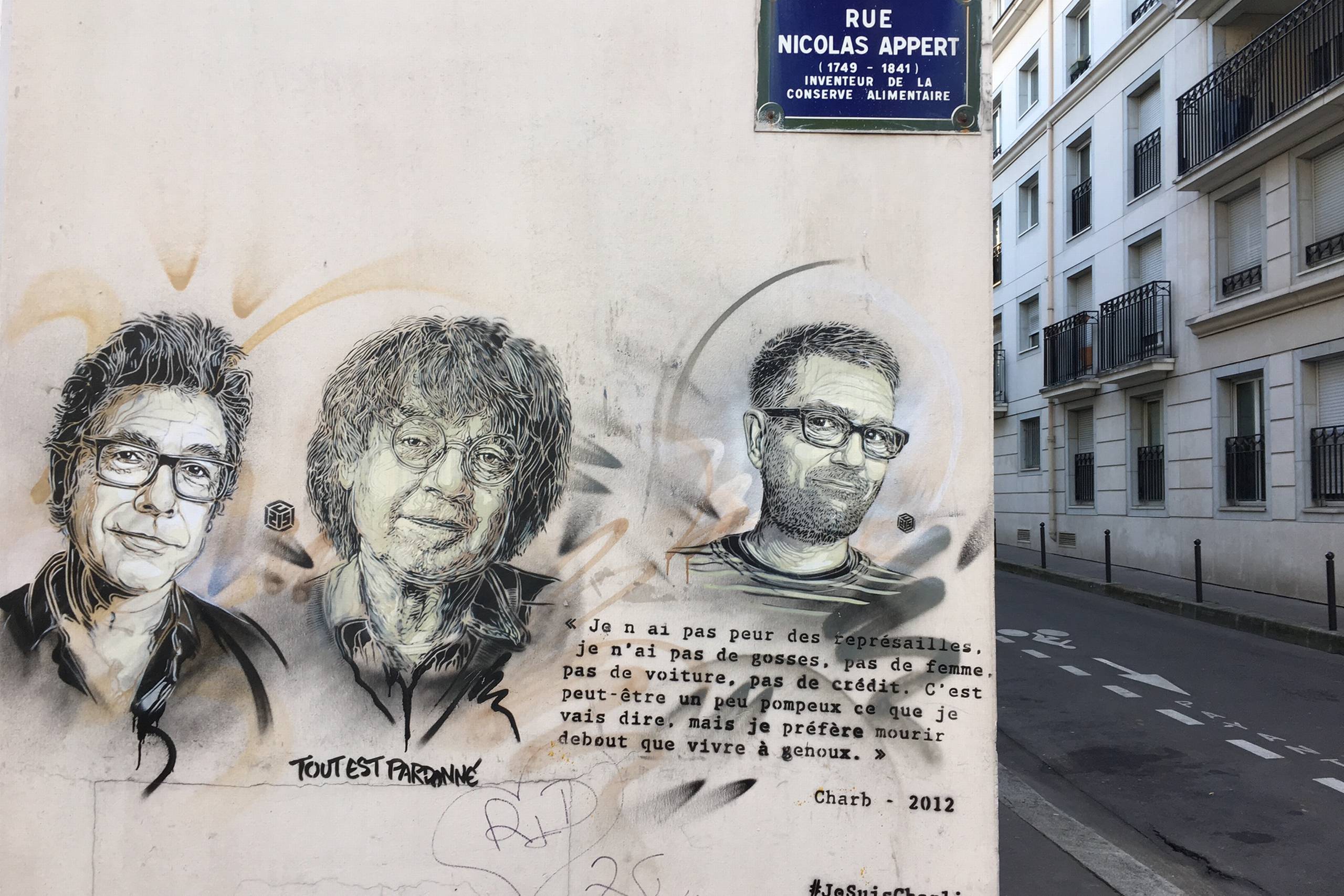 På en mur tæt på Charlie Hebdos gamle redaktionslokaler i Rue Nicolas Appert har en kunstner tegnet disse portrætter af tre af satiremagasinets kendte tegnere, som mistede livet under terrorangrebet den 7. januar 2015. Fra venstre ser man Tignous (Bernard Verlhac Tignous), Cabu (Jean Cabut) og Charb (Stéphane Charbonnier). Foto: Marie Louise Albers/JP.