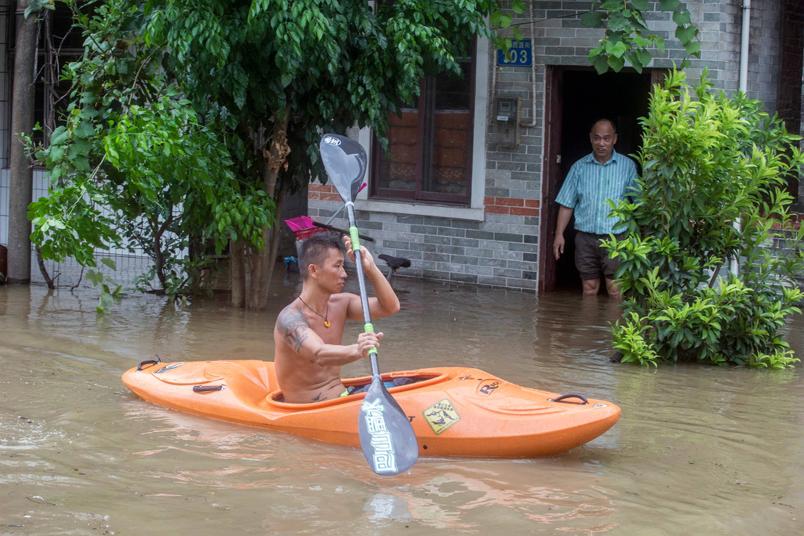 En lokal padlede onsdag gennem en oversvømmet gade i Guangzhou i Kinas Guangdong-provins. Foto: Chinatopix/AP